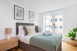 ein weißes Schlafzimmer mit einem großen Bett mit Kissen in der Unterkunft Fitzrovia & Soho with Balcony - CityApartmentStay in London