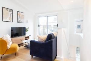 ein Wohnzimmer mit einem Sofa und einem TV in der Unterkunft Fitzrovia & Soho with Balcony - CityApartmentStay in London