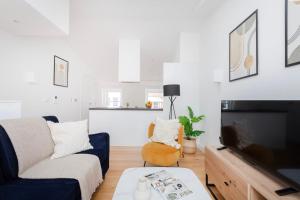 ein Wohnzimmer mit einem Sofa und einem TV in der Unterkunft Fitzrovia & Soho with Balcony - CityApartmentStay in London