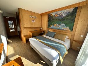 1 dormitorio con 1 cama y una gran pintura en la pared en Hotel Le Soly, en Morzine