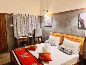 1 dormitorio con 1 cama con sábanas blancas y almohadas de color naranja y blanco en Yala Leopard Lodge, en Yala