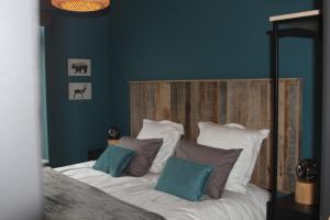 a bedroom with a bed with a wooden headboard and pillows at Au Cerf & Fagnes in Spa
