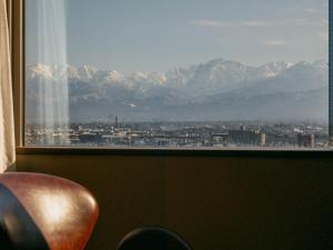 a window with a view of a city and mountains at Oarks Canal Park Hotel Toyama in Toyama