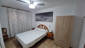 a bedroom with a white bed and a wooden cabinet at Adosado Puntamer Orangecosta in Peñíscola