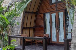 Cabaña de madera con mesa y sillas en una terraza en Omah Gili Hotel en Gili Air