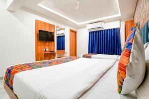 a bedroom with a large white bed and blue curtains at FabHotel Nobel Inn in Ahmedabad