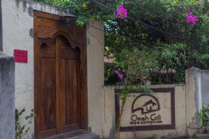 uma porta de madeira no lado de um edifício com um sinal em Omah Gili Hotel em Gili Air