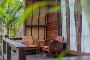 a porch with chairs and a table on a house at Omah Gili Hotel in Gili Air