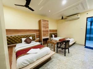 a bedroom with two beds and a desk in it at HOTEL AUGUSTO in Varanasi