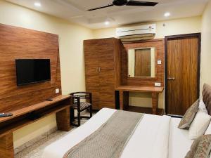 a bedroom with a bed and a desk and a television at HOTEL AUGUSTO in Varanasi