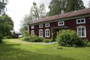 een rood huis met witte ramen en een tuin bij Ralph Lundstengården (Farmhouse Lodge) in Luleå