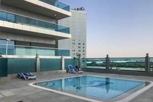 a swimming pool on top of a building with two chairs at Frank Porter - Elite Business Bay Residence in Dubai