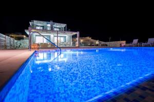 a swimming pool at night with a house in the background at Francis & Gregorys Luxury Villas in Afantou