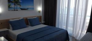 a bedroom with a bed with blue pillows and a window at Anxhelos Hotel in Himare