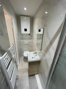 a white bathroom with a sink and a mirror at studio 9 neuf et moderne in Tremblay En France