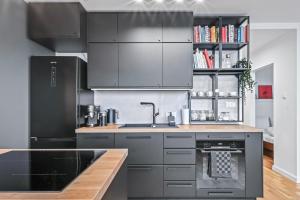 uma cozinha com armários pretos e um lavatório em RentPlanet - Apartament Komorska em Varsóvia