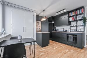 uma cozinha com armários pretos e uma mesa e cadeiras em RentPlanet - Apartament Komorska em Varsóvia