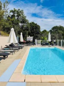 a swimming pool with lounge chairs and umbrellas at GITE des teilles in Carlux