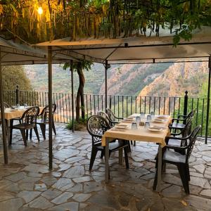 un patio con mesas, sillas y una sombrilla en Kampaoh Sierra Nevada, en Güéjar-Sierra