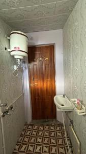 baño con lavabo y puerta de madera en Bagheecha Homestay, en Kanatal