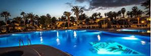 a large blue swimming pool at a resort at night at Las Brisas, Villa 98 in Playa Blanca