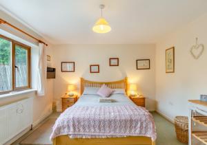 ein Schlafzimmer mit einem Bett, zwei Nachttischen und einem Fenster in der Unterkunft Alvaston in Looe