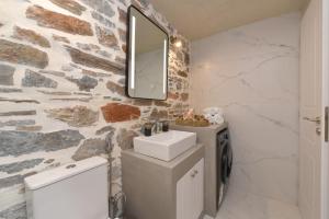 a bathroom with a sink and a stone wall at Alesio's house in Ermoupoli
