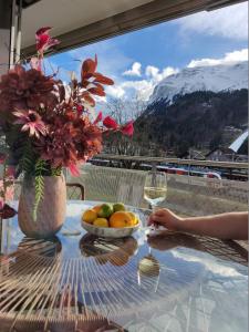 a table with a bowl of fruit and a glass of wine at Central Serviced Apartments in Engelberg