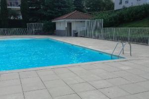 a blue swimming pool in a yard with a fence at Logement à Tassin avec piscine et garage in Tassin-la-Demi-Lune