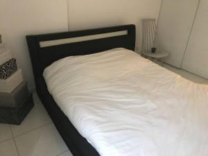 a bed with a black frame and white sheets at Logement à Tassin avec piscine et garage in Tassin-la-Demi-Lune