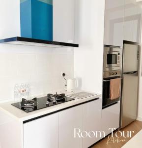 a white kitchen with a stove and a refrigerator at Beacon Executive@Penang Georgetown in George Town