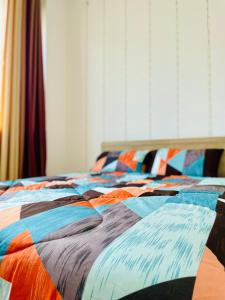 Una cama con un edredón colorido en un dormitorio en Stress-Free Cozy Private Room - heart of the city, en Abu Dabi