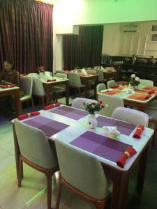 uma sala de jantar com mesas e cadeiras e uma pessoa sentada à mesa em MCLORRETS SUITES em Enugu