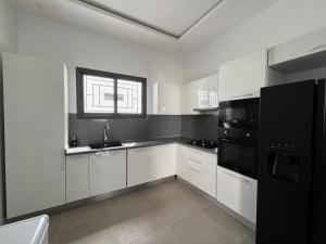 a kitchen with white cabinets and black appliances at Lovers Villa Somone in Somone