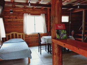 a bedroom with a bed and a table and a window at Cabaña Las Flores in Potrerillos