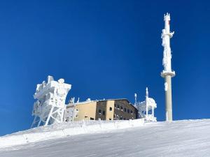 um edifício no topo de uma colina nevada com um poste em Koralm Appartement 7 em Wolfsberg