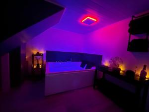 a living room with a couch and purple lights at Maison à la campagne avec piscine privée et balnéo in Sendets