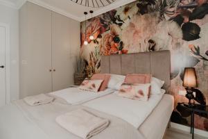 sypialnia z dużym białym łóżkiem i tapetą w kwiaty w obiekcie TOTU HOME Harmonia Oliwska Gdańsk w Gdańsku