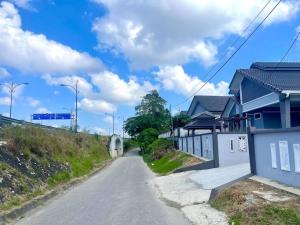 an empty road next to a house on a hill at Rumah Tok Wan Dee (House 5 Rooms) 2024 in Wakaf Baharu