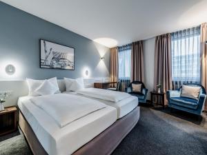 una camera d'albergo con un grande letto e una sedia di Hotel Royal a Stoccarda