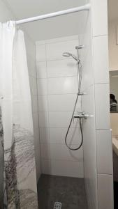 ein Bad mit einer Dusche an einer weißen Wand in der Unterkunft Chillax Ferienhaus für Familie und Urlauber in Köln