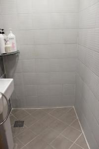 a bathroom with a shower with white tiled walls at Hostel JL in Chung-jeong in Seoul