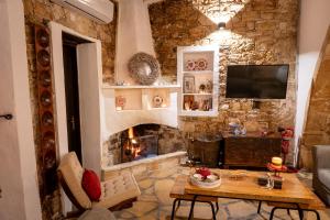 a living room with a stone wall with a fireplace at Oinoessa Traditional Boutique Guest Houses in Lofou