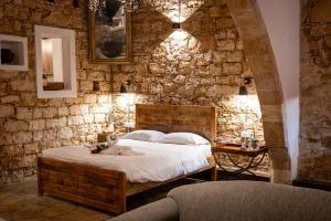 ein Schlafzimmer mit einem Bett und einer Steinmauer in der Unterkunft Oinoessa Traditional Boutique Guest Houses in Lofou