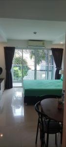 バンサレーにあるSea Saran Condominium for Short-Term Stayのベッドルーム(緑のベッド1台、テーブル付)