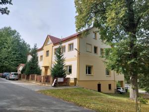 une grande maison jaune avec des voitures garées dans une allée. dans l'établissement Ubytování Hamry, à Hlinsko
