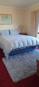 ein Schlafzimmer mit einem großen Bett mit einem Teppich in der Unterkunft Rakaia Huts Holiday Home in Southbridge