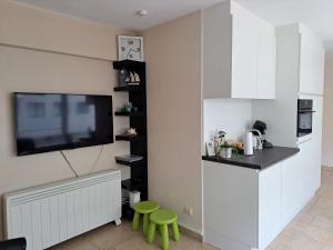 eine Küche mit weißen Schränken und einem TV an der Wand in der Unterkunft Apartment Gounod Nieuwpoort in Nieuwpoort
