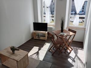 ein Wohnzimmer mit einem Tisch, Stühlen und einem TV in der Unterkunft Poisson in Isigny-sur-Mer