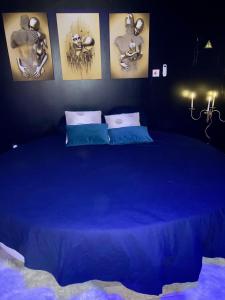 a blue bed in a room with pictures on the wall at Hôtel Le Gambetta in Vias